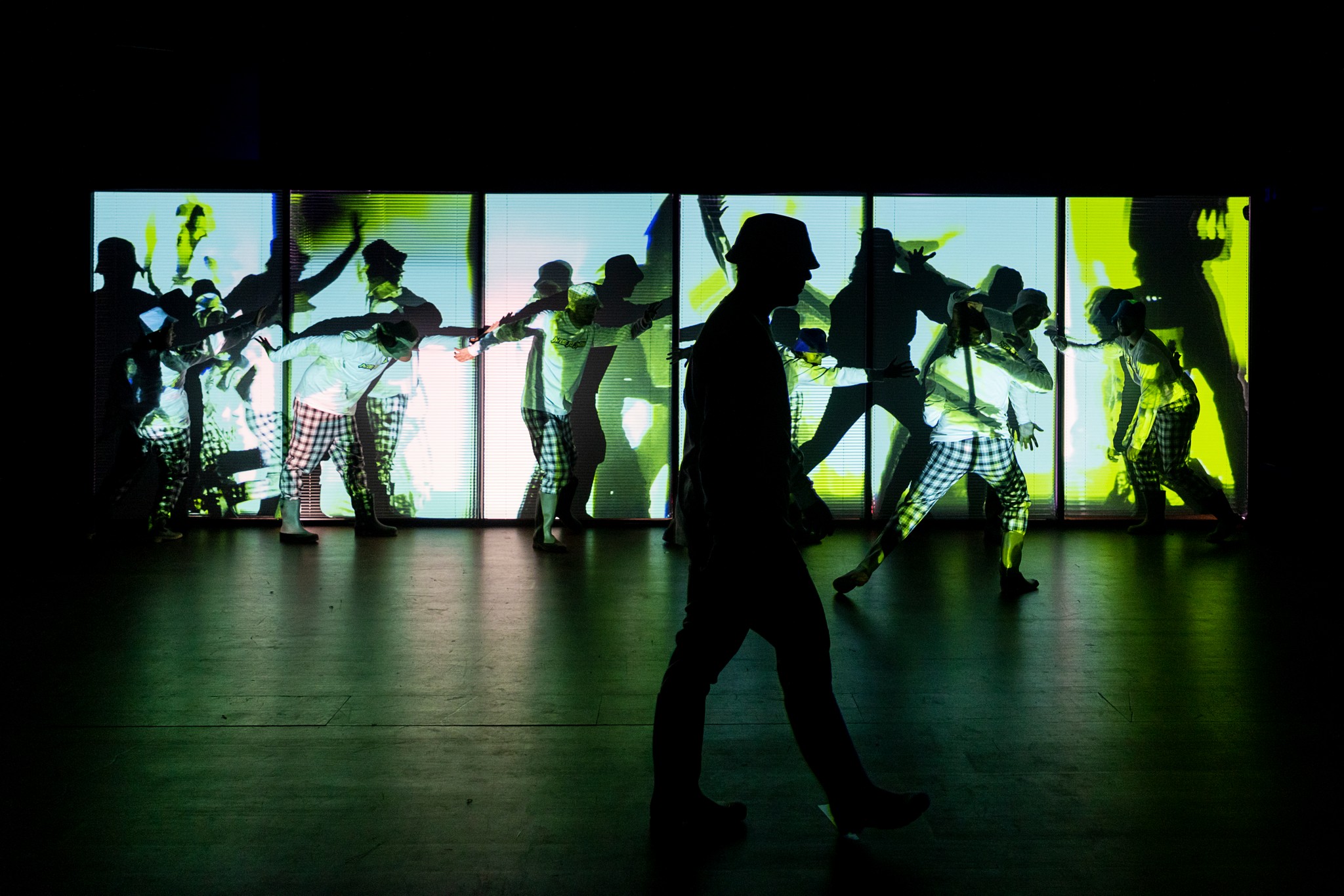 Performers silhouetted in front of an illuminated stage installation